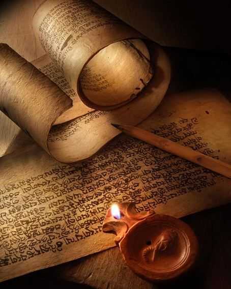 Ancient papyrus scrolls beside a burning oil lamp - the transmission of the sacred texts