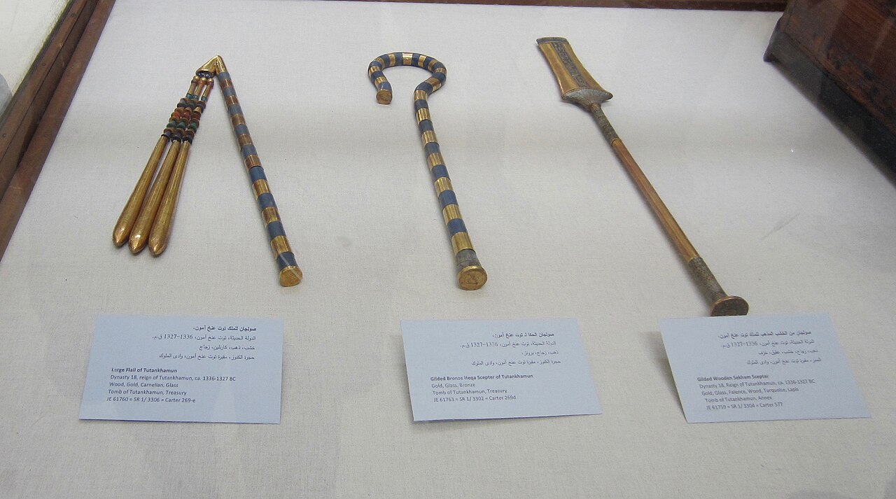 Complete gold and coloured regalia from Tutankhamun's tomb: flail at left, curved crook at centre and broad-headed sekhem sceptre at right.