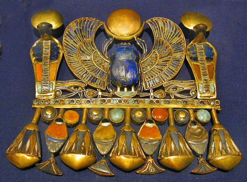 Tutankhamun’s complete gold pectoral with a blue winged scarab, solar disk, paired cobras, and lotus fringe.