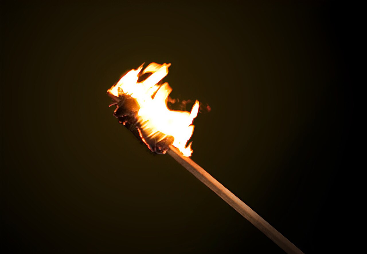 A burning torch with a bright flame against a dark background