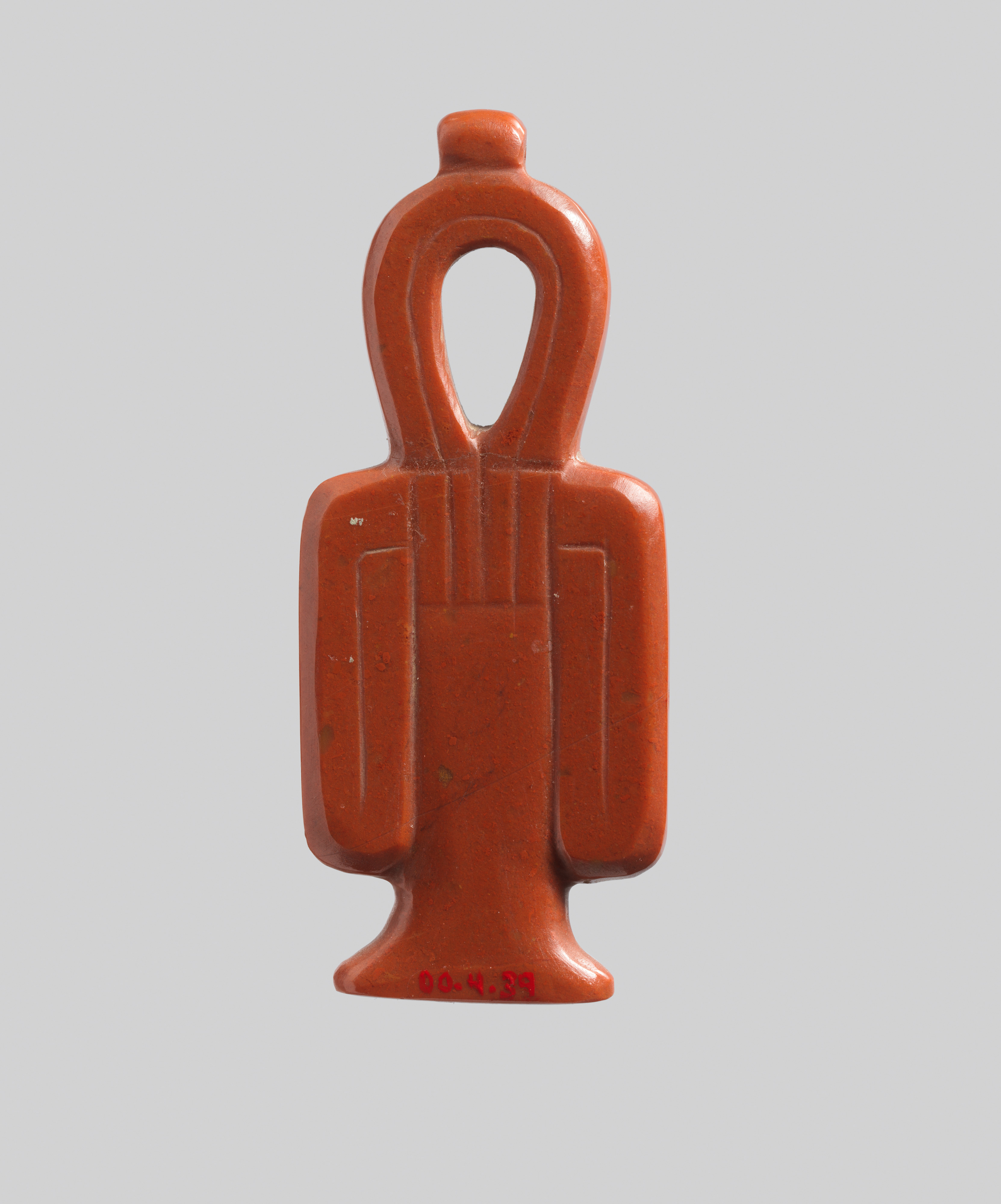 An intact polished red-jasper tyet amulet, with an open upper loop, central binding, and two descending folded sides.