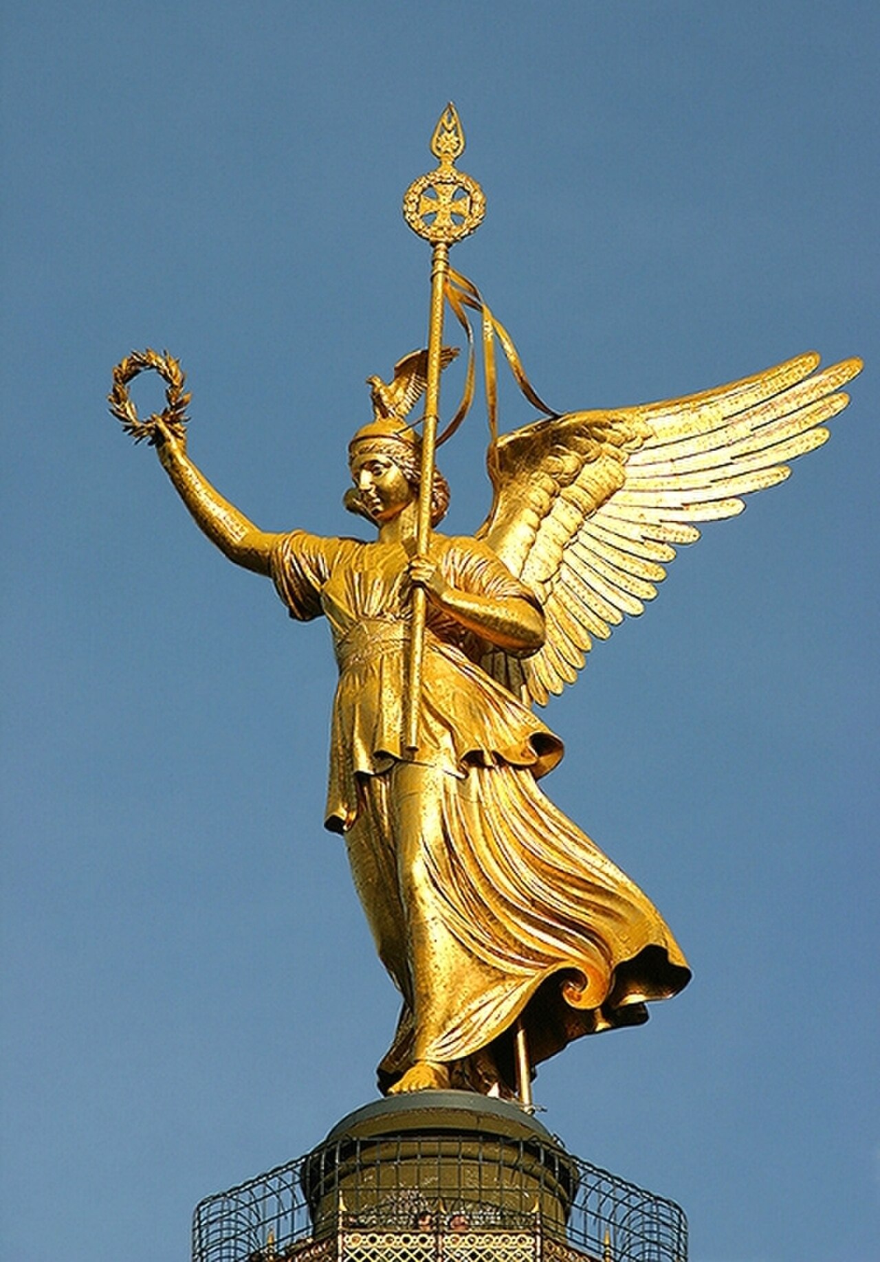 A complete golden winged Victoria raises a wreath above the Berlin Victory Column against a deep blue sky.