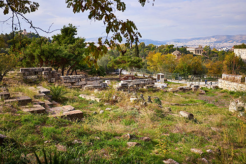 Ruins of an ancient sanctuary among trees, a Doric temple in the distance