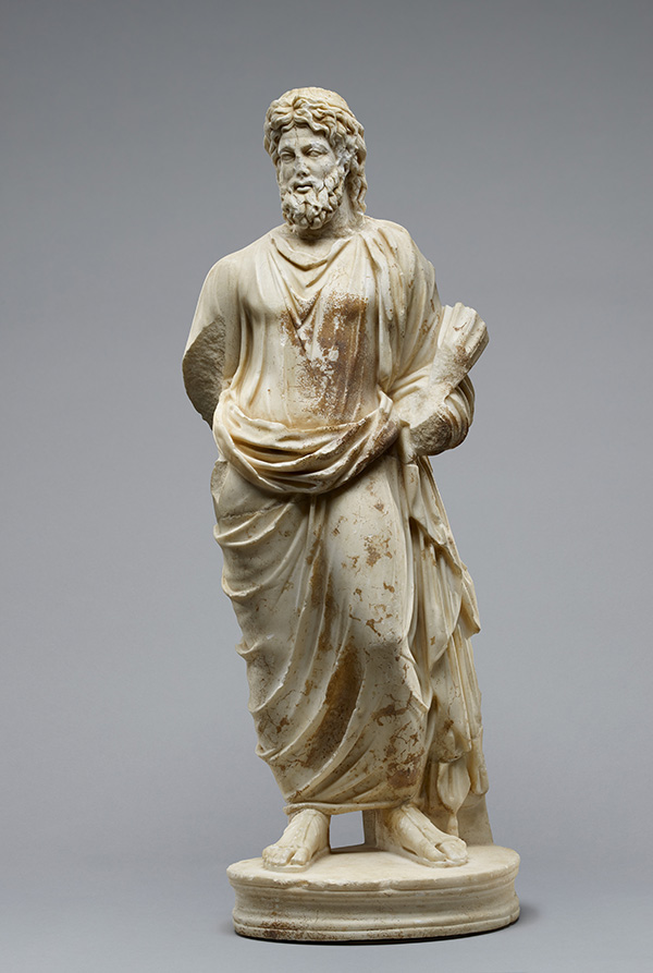 A marble statuette of a bearded God standing in a mantle