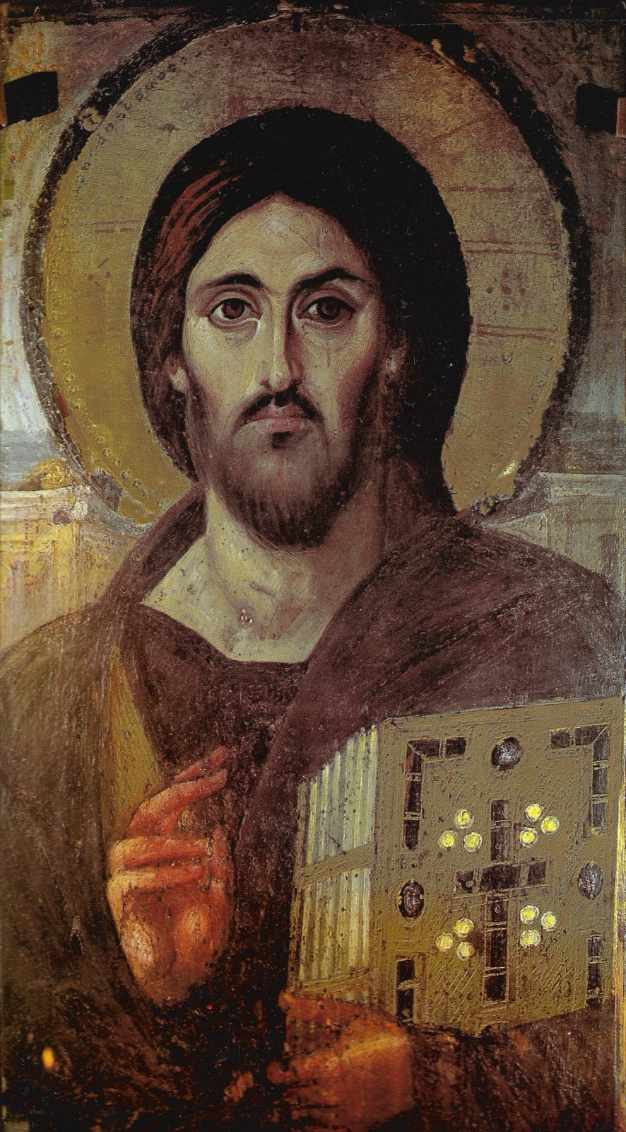 A Byzantine painted icon of a bearded Christ with long dark hair and a cross-inscribed halo, holding a jewelled book and raising his right hand in blessing.