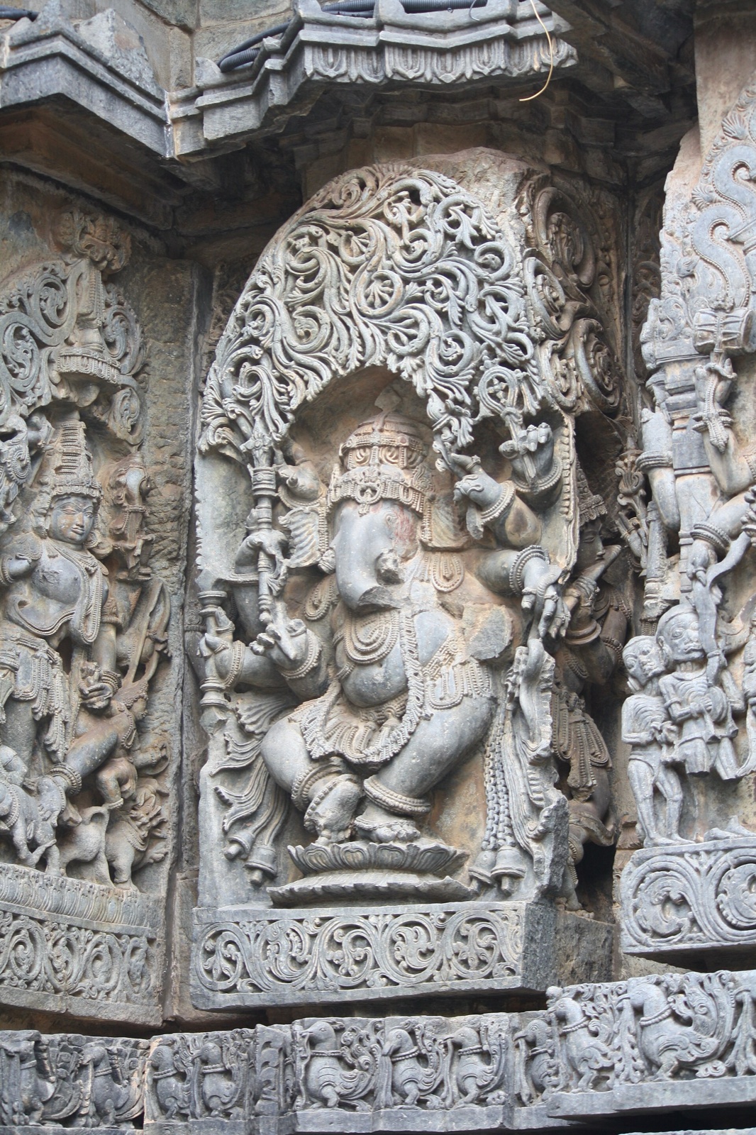 Stone sculpture of the elephant-headed God Ganesha dancing, carved on a temple wall.