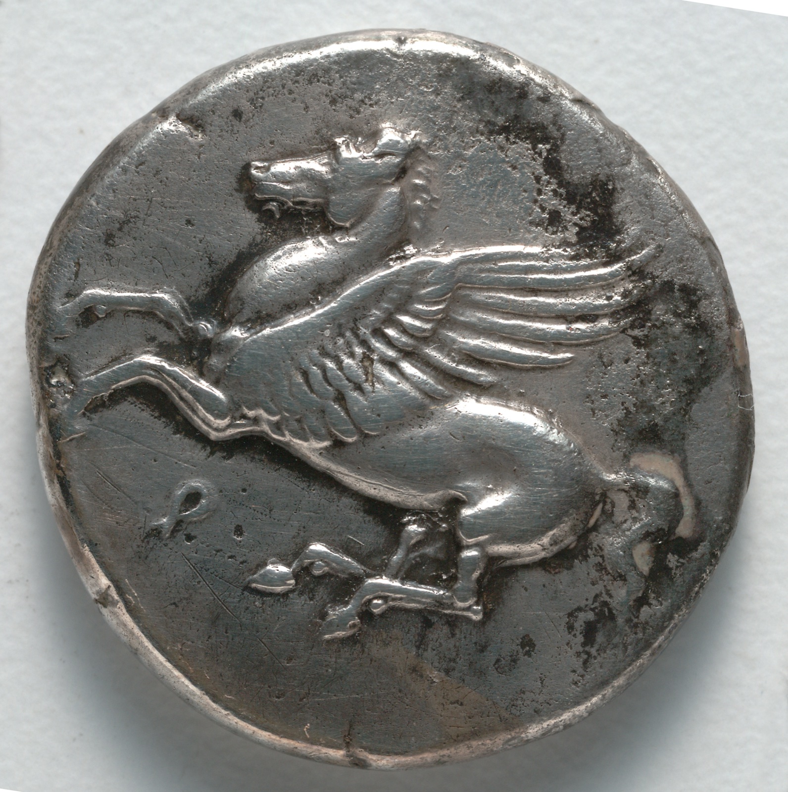 Silver coin showing the winged horse Pegasus leaping to the left with forelegs raised.