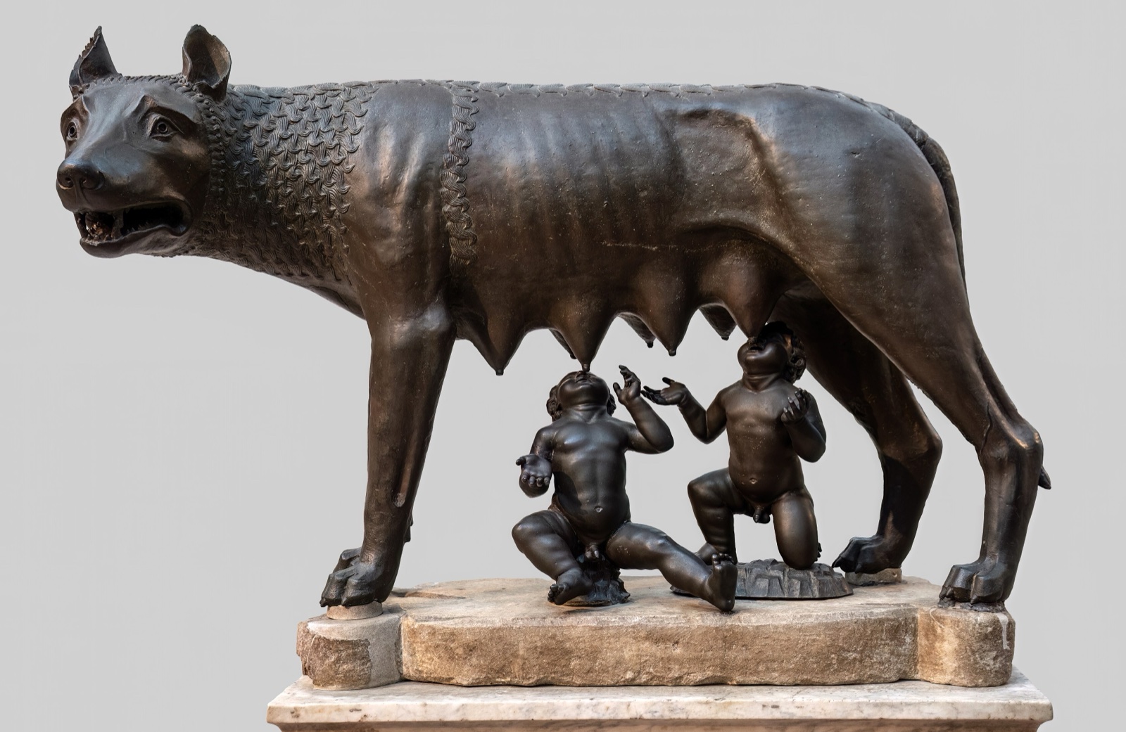 Bronze she-wolf standing, with the infant twins Romulus and Remus suckling beneath her.
